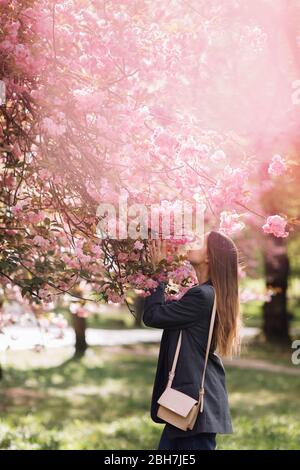 belle fille aime le parfum de l'arbre fleuri. Portrait de belle femme avec cerisier fleuri - fille inhale parfum des fleurs avec Banque D'Images