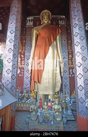 Statue d'or du Bouddha, drapée d'une ceinture d'orange, dans un temple à la décoration élaborée ou wat à Luang Prabang, Laos, Asie du Sud-est. La ville de Luang Prabang est classée au patrimoine mondial de l'UNESCO. Banque D'Images