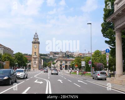 Bergame, Italie - 06 août 2019: Tour Torre dei Caduti à la Piazza Vittorio Veneto dans la partie inférieure de la ville de Bergame avec la ville fortifiée en haut Banque D'Images
