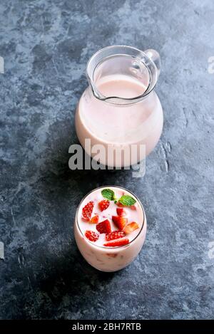 Yaourt à la fraise avec baies fraîches en verre sur fond de pierre bleue. Concept de nourriture et de boisson saine. Banque D'Images