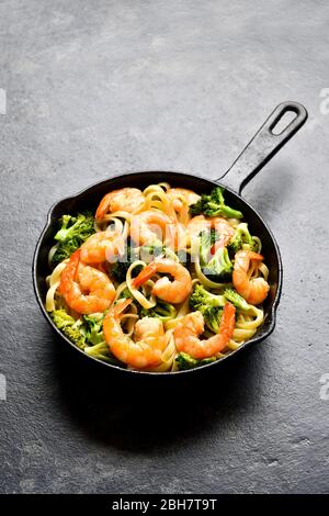 Crevettes et pâtes de brocoli dans une poêle en fonte sur fond de pierre sombre avec espace texte libre. Un délicieux plat sain pour le dîner. Banque D'Images