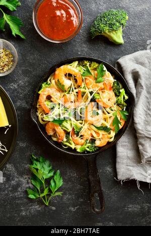 Crevettes et pâtes de brocoli dans une poêle en fonte sur fond de pierre sombre. Délicieux plat sain pour le dîner. Vue sur le dessus, plat Banque D'Images