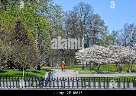 Personne non reconnaissable entrant dans le parc Carl Johans avec la statue du roi Karl Johan XIV au début du printemps à Norrkoping. Banque D'Images