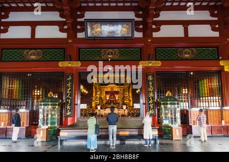 Le Japon, Honshu, Tokyo, Asakusa, Temple Sensoji, les gens prier à l'intérieur de la salle principale Banque D'Images