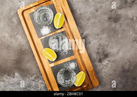 Tequila projectiles, limes et sel sur planche en bois sur fond gris. Vue de dessus, espace de copie Banque D'Images