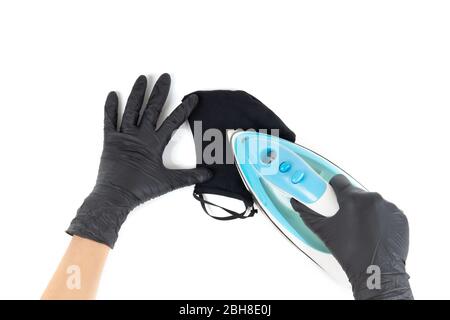 Les mains féminines dans des gants jetables noirs fer un masque noir réutilisable en coton. Vue de la première personne, isolée sur blanc. Banque D'Images