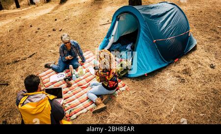 Les gens apprécient le camping gratuit dans la forêt de pins à l'aide de la technologie ordinateur portable et mobile phoner et détendu de la société de stress - style de vie extérieur pour les voyageurs alternatifs - vue de dessus Banque D'Images