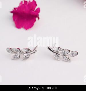 Une paire de superbes boucles d'oreilles en argent 925 en forme de feuilles décorées de diamant isolé sur fond gris Banque D'Images