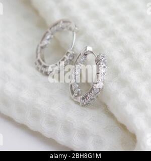 Une paire de superbes boucles d'oreilles en argent 925, décorées de diamants sur un tissu blanc Banque D'Images