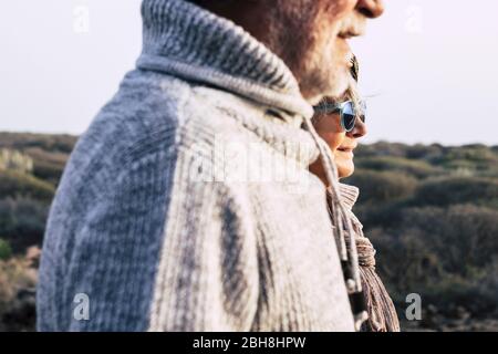 Portrait fashion style vieux couple de seniors homme et femme avec la nature en arrière-plan - la saison froide de l'automne ou au printemps et soleil Banque D'Images