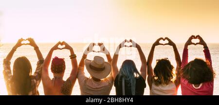Groupe de diversité alternative jeune femme profitant du coucher du soleil sur la mer faisant symbole de coeur avec les mains - les gens qui jouissent d'un style de vie amical - vacances dans le concept d'amitié pour les femmes Banque D'Images