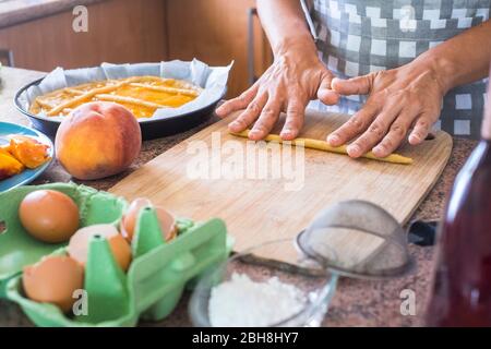 gros plan sur les mains de la femme préparant un gâteau avec des ingrédients frais crus naturels comme les pâtes farina pêche et oeufs et l'eau pour une nourriture saine mais savoureuse pour les parents et les amis à la maison - travailler dans le concept de cuisine Banque D'Images