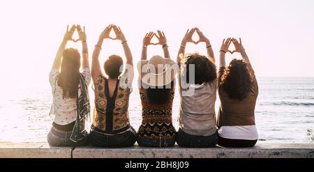 Groupe de jeunes femmes militantes vues de l'arrière faisant symbole féminisme et puissance féminine et respect des mains - soleil et nature extérieure et coucher de soleil en arrière-plan pour les groupes Banque D'Images