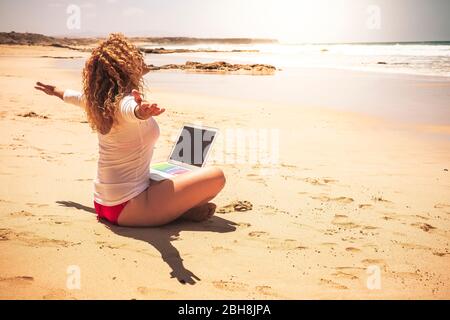 Heureux personnes libres caucasienne femme assis à l'ebach avec ordinateur portable sur ses jambes ouvrant les bras profiter de la liberté pour les vacances d'été et pour travailler sans stress bureau dans la ville Banque D'Images