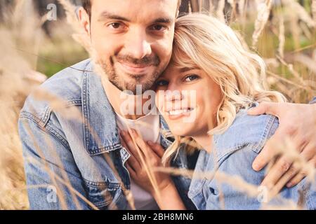 Un jeune couple heureux assis parmi des plantes sauvages Banque D'Images