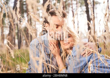 Un jeune couple heureux assis parmi des fleurs sauvages Banque D'Images