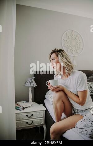 Frau mit Kaffeetasse im Bett Banque D'Images