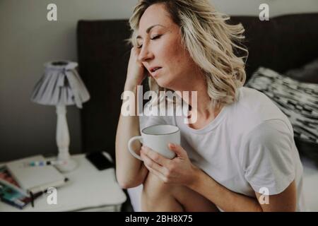 Frau mit Kaffeetasse im Bett, müde, unausgeschlafen Banque D'Images