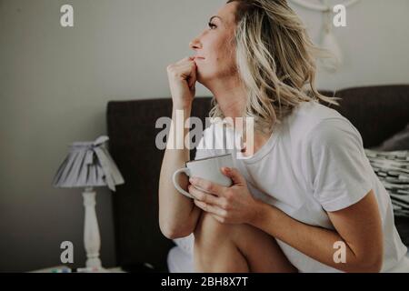Frau mit Kaffeetasse im Bett Banque D'Images