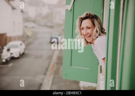 Frau blickt fröhlich aus dem Fenster Banque D'Images