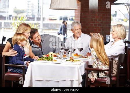 Une famille heureuse prend des photos au restaurant avec un appareil photo Banque D'Images