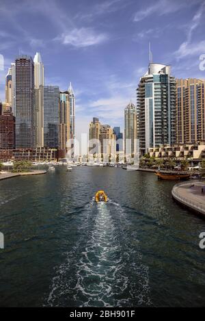 Blick auf ein Boot das gerade in den Hafen von Dubai Marina fährt, Uferpromenade und moderne Wolkenkratzer Banque D'Images