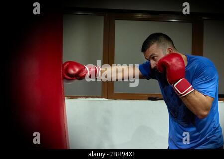 Vue latérale du boxeur homme confiant qui fait de l'exercice dans la salle de sport Banque D'Images