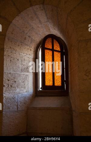 Fenêtre en verre orange ouverte avec des barreaux croisés, des chutes de lumière en Israël, Nazareth, église d'Annonciation, basilique d'Annonciation Banque D'Images