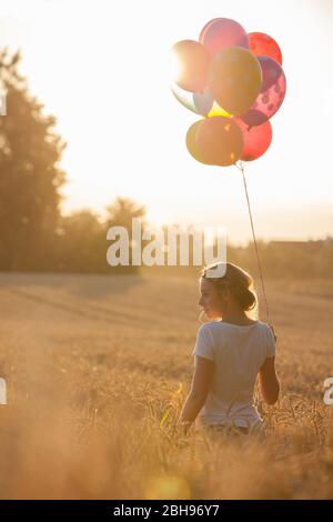 Jeune femme avec des ballons d'air colorés dans le champ de maïs propre Banque D'Images