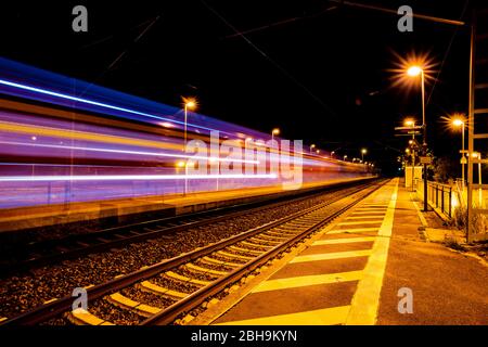 Longue exposition de trains en train dans la nuit dans une gare Banque D'Images