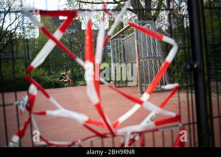 Hambourg, Allemagne. 24 avril 2020. Les entrées d'un petit terrain de football public dans le quartier d'Eimsbüttel sont bloquées par des bandes de barrière rouge et blanche. Crédit: Christian Charisius/dpa/Alay Live News Banque D'Images