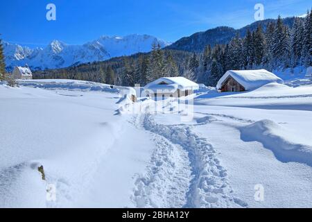 Cabanes enneigées de Winterly avec les montagnes de Karwendel dans l'Elmau, à Klais, Mittenwald, Haute-Bavière, Bavière, Allemagne Banque D'Images