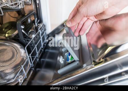 Gros plan sur la tablette manuelle dans la boîte à lessive du lave-vaisselle, mise au point douce. Concept de plats sales. Banque D'Images