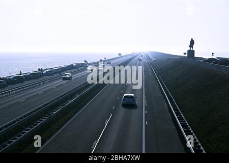 Vue sur l'Afsluitdijk aux pays-Bas en contre-jour et tons bleus monochromes avec la statue de Cornelis Lely en hiver. Banque D'Images