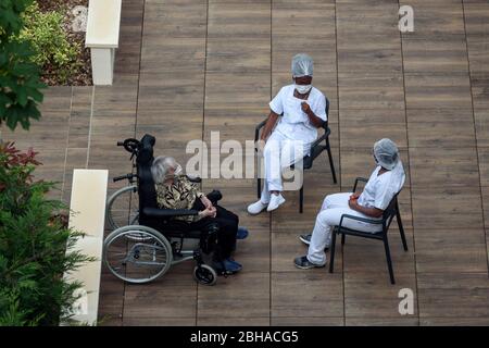 Infirmières et infirmiers s'occupant de personnes âgées dans une maison de soins pendant la pandémie de coronavirus. Les soignants qui ont une pause au soleil avec une vieille femme résidente. Banque D'Images