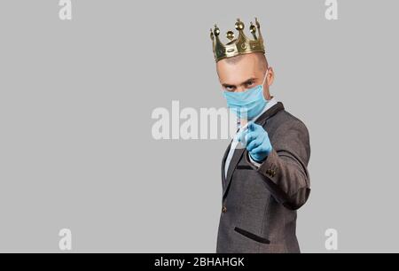 Jeune homme d'affaires dans une couronne et un masque de protection et des gants. Rester à la maison pendant la quarantaine du coronavirus Covid-19. Espace vide pour le texte. Banque D'Images