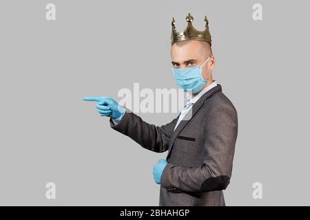 Jeune homme d'affaires dans une couronne et un masque de protection et des gants. Rester à la maison pendant la quarantaine du coronavirus Covid-19. Espace vide pour le texte. Banque D'Images