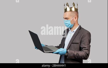 Jeune homme d'affaires dans une couronne et un masque de protection et des gants. Rester à la maison pendant la quarantaine du coronavirus Covid-19. Espace vide pour le texte. Banque D'Images