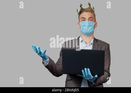 Jeune homme d'affaires dans une couronne et un masque de protection et des gants. Rester à la maison pendant la quarantaine du coronavirus Covid-19. Espace vide pour le texte. Banque D'Images