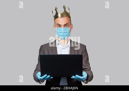 Jeune homme d'affaires dans une couronne et un masque de protection et des gants. Rester à la maison pendant la quarantaine du coronavirus Covid-19. Espace vide pour le texte. Banque D'Images