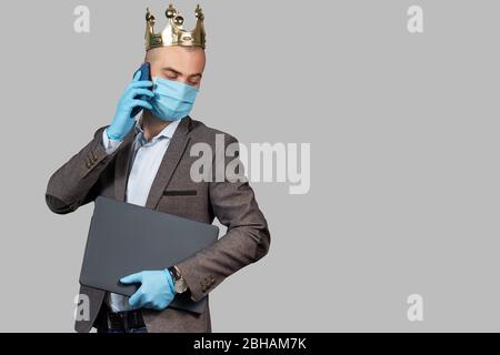 Jeune homme d'affaires dans une couronne et un masque de protection et des gants. Rester à la maison pendant la quarantaine du coronavirus Covid-19. Espace vide pour le texte. Banque D'Images