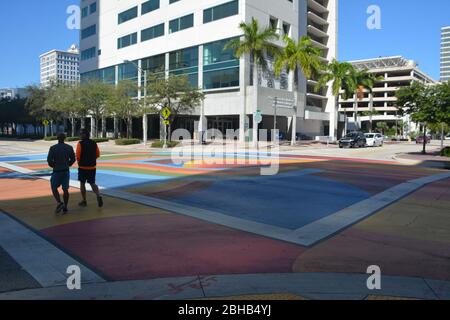 Deux personnes marchant sur Las Olas Boulevard à fort Lauderdale, en Floride, avec un passage à niveau coloré et un bâtiment de campus Broward College en face. Banque D'Images