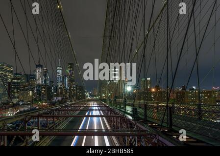 Vue sur le pont de Brooklyn la nuit jusqu'aux gratte-ciel éclairés de Manhattan Banque D'Images