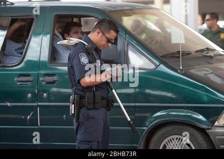 Laredo, Texas États-Unis, 14 juillet 2010: Des agents fédéraux, y compris la patrouille frontalière des États-Unis (vert), les douanes américaines (bleu) et les adjoints du shérif du comté de Webb inspectent les voitures en direction du Mexique au port d'entrée de Laredo, au Texas. Les agents sont à la recherche d'argent et de drogues qui se dirigent vers le Mexique à la suite de la violence accrue et du trafic de drogues le long de la frontière. ©Marjorie Kamys Cotera/Bob Daemmrich Photographie Banque D'Images