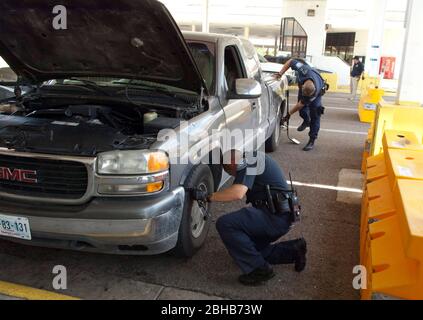 Laredo, Texas États-Unis, 14 juillet 2010: Des agents fédéraux, y compris la patrouille frontalière des États-Unis (vert), les douanes américaines (bleu) et les adjoints du shérif du comté de Webb inspectent les voitures en direction du Mexique au port d'entrée de Laredo, au Texas. Les agents sont à la recherche d'argent et de drogues qui se dirigent vers le Mexique à la suite de la violence accrue et du trafic de drogues le long de la frontière. ©Marjorie Kamys Cotera/Bob Daemmrich Photographie Banque D'Images