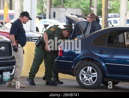 Laredo, Texas États-Unis, 14 juillet 2010: Des agents fédéraux, y compris la patrouille frontalière des États-Unis (vert), les douanes américaines (bleu) et les adjoints du shérif du comté de Webb inspectent les voitures en direction du Mexique au port d'entrée de Laredo, au Texas. Les agents sont à la recherche d'argent et de drogues qui se dirigent vers le Mexique à la suite de la violence accrue et du trafic de drogues le long de la frontière. ©Marjorie Kamys Cotera/Bob Daemmrich Photographie Banque D'Images