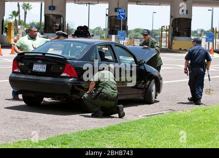 Laredo, Texas États-Unis, 14 juillet 2010: Des agents fédéraux, y compris la patrouille frontalière des États-Unis (vert), les douanes américaines (bleu) et les adjoints du shérif du comté de Webb inspectent les voitures en direction du Mexique au port d'entrée de Laredo, au Texas. Les agents sont à la recherche d'argent et de drogues qui se dirigent vers le Mexique à la suite de la violence accrue et du trafic de drogues le long de la frontière. ©Marjorie Kamys Cotera/Bob Daemmrich Photographie Banque D'Images