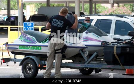 Laredo, Texas États-Unis, 14 juillet 2010: Des agents fédéraux, y compris la patrouille frontalière des États-Unis (vert), les douanes américaines (bleu) et les adjoints du shérif du comté de Webb inspectent les voitures en direction du Mexique au port d'entrée de Laredo, au Texas. Les agents sont à la recherche d'argent et de drogues qui se dirigent vers le Mexique à la suite de la violence accrue et du trafic de drogues le long de la frontière. ©Marjorie Kamys Cotera/Bob Daemmrich Photographie Banque D'Images