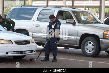 Laredo, Texas États-Unis, 14 juillet 2010 : l'agent des douanes des États-Unis utilise un miroir pour inspecter le dessous de la voiture qui se dirige vers le Mexique au port d'entrée de Laredo, TX. Les agents sont à la recherche d'argent et de drogues qui se dirigent vers le Mexique à la suite de la violence accrue et du trafic de drogues le long de la frontière. ©Marjorie Kamys Cotera/Bob Daemmrich Photographie Banque D'Images