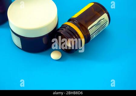 Pilules blanches et bouteilles de verre pour pilules sur fond bleu pilules de verre dispersé sur fond bleu. Banque D'Images